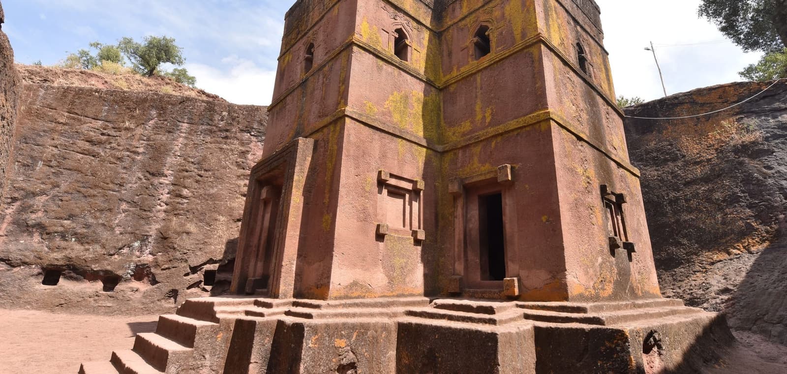 The rock-hewn church of Bete Giyorgis at Lalibela, cut down into red stone below ground level, with its stepped base and carved windows.