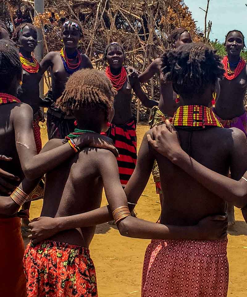 Hamar women in beaded necklaces and patterned cloth gathered closely together at a celebration in southern Ethiopia.