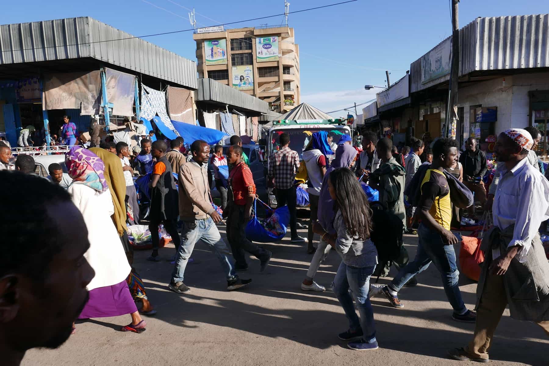A busy street market in Addis Ababa, with people walking between stalls and shopfronts.