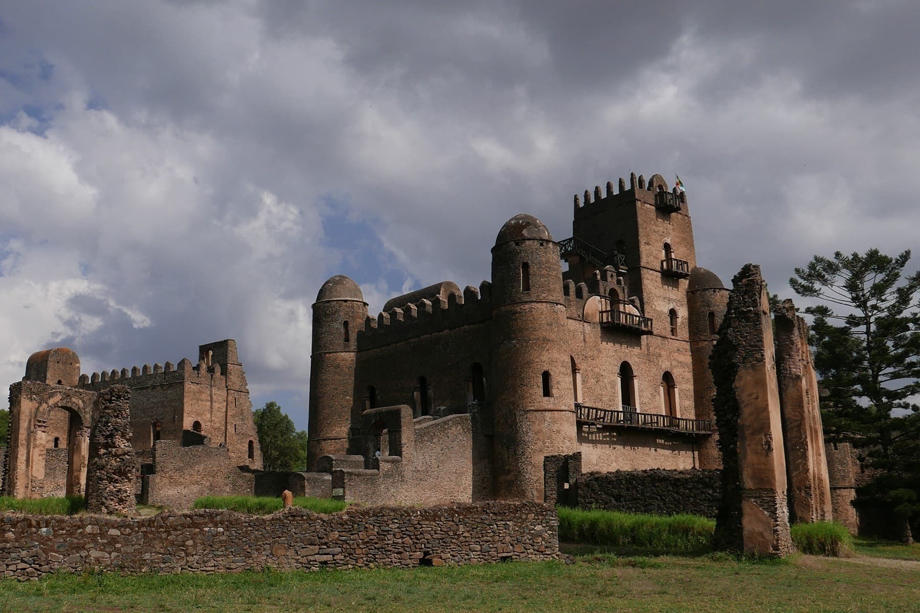 The stone castle at Fasil Ghebbi in Gondar, with round corner towers under a clouded sky.
