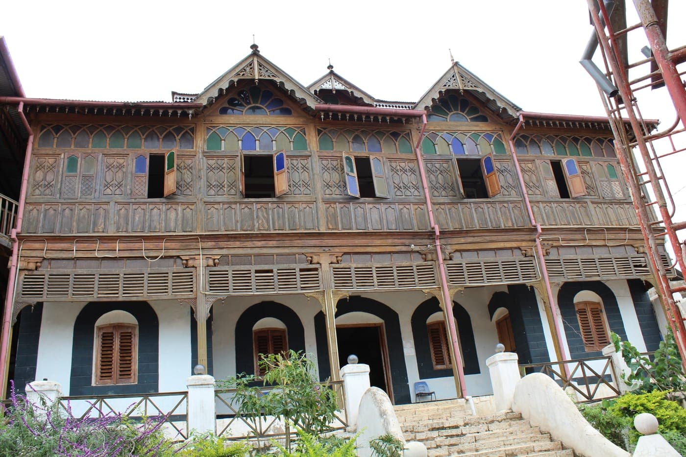 A tall Harari merchant house in Harar, its upper storey wrapped in carved and painted wooden balconies above a white facade.